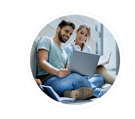 Two young adults sit together and look at a laptop with a smile.