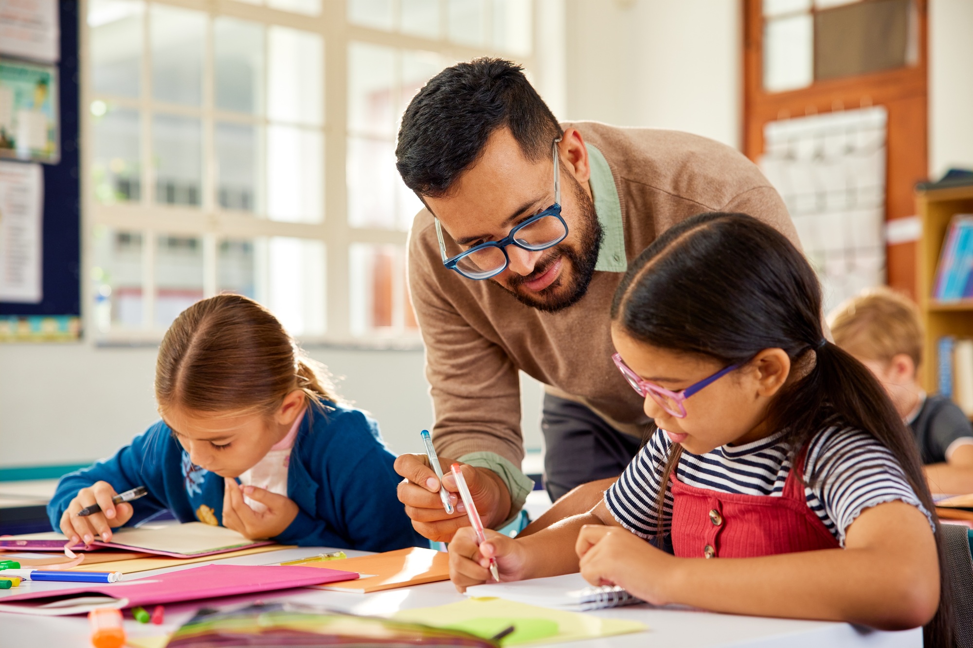 Teacher helping schoolchildren during lesson in classroom